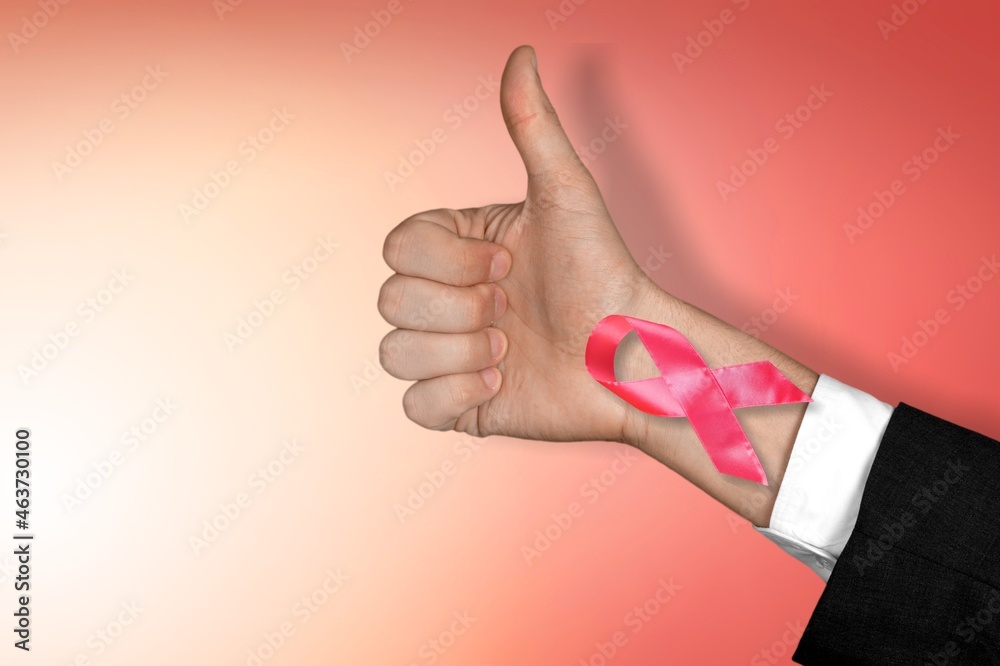First of person top view, raised female hand with a ribbon, cancer awareness First of person top view, raised female hand with a ribbon, cancer awareness