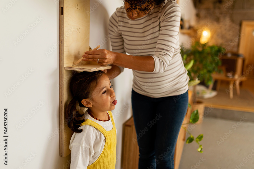 © Valentina Barreto/Stocksy - Mother measuring her daughter's growth © Valentina Barreto/Stocksy - Mother measuring her daughter's growth