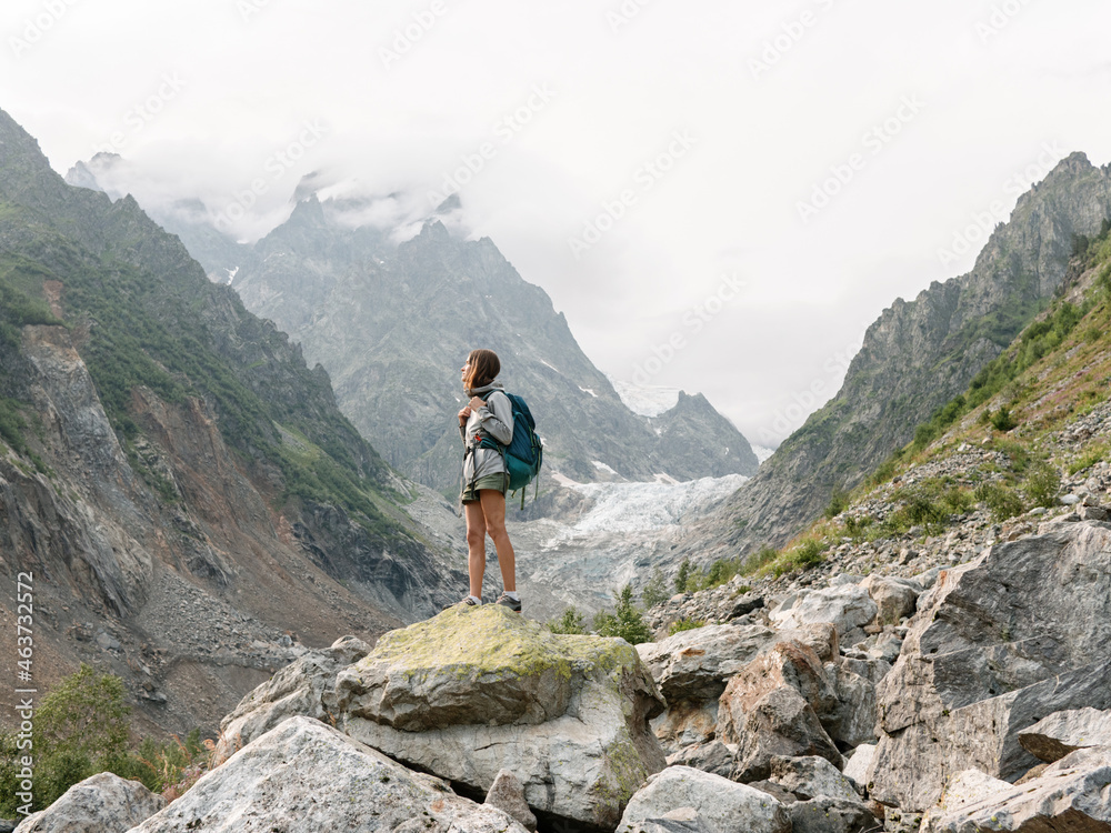 Female traveller standing on the rock in mountain area Female traveller standing on the rock in mountain area