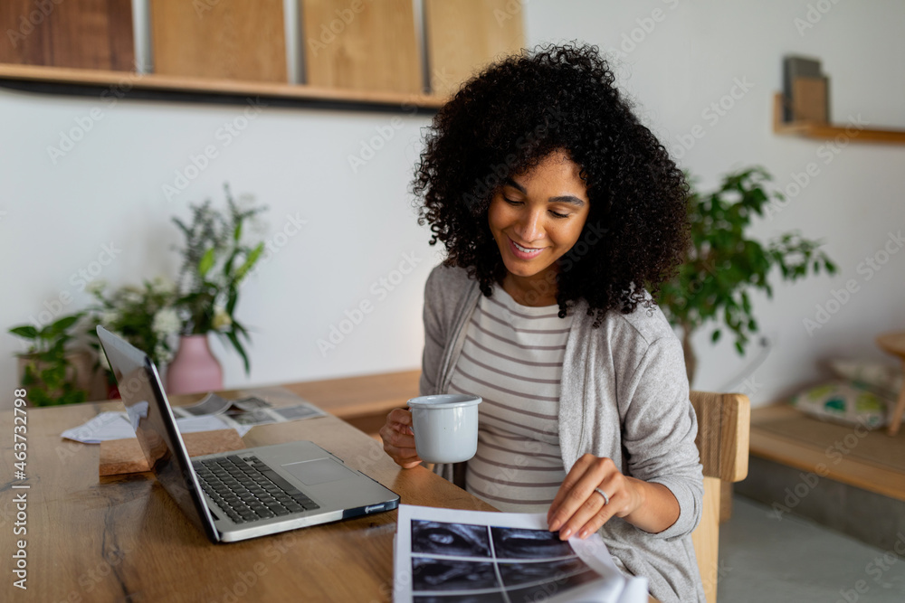 Pregnant woman looking at ultrasounds at home office Pregnant woman looking at ultrasounds at home office