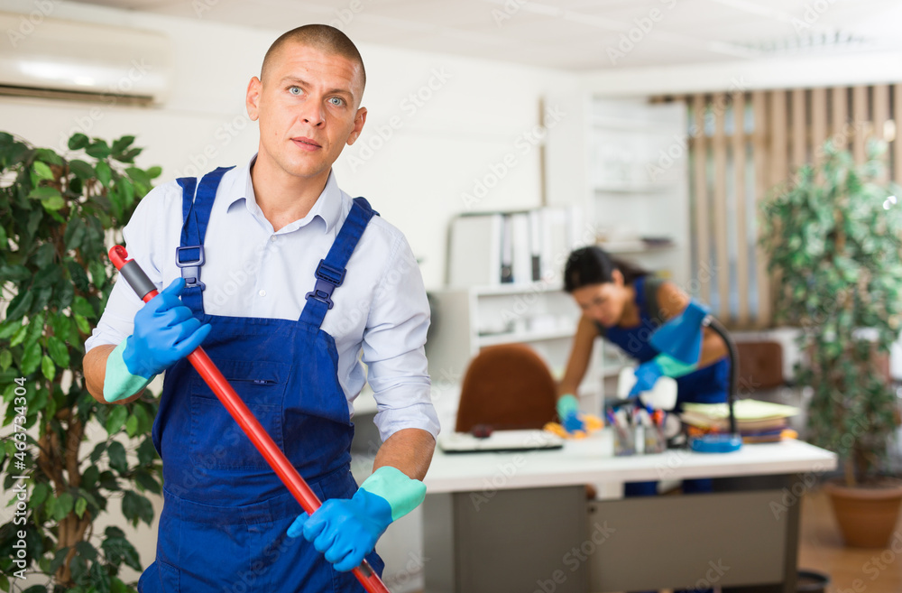 Fototapeta premium Positive male worker from cleaning service, wiping office floor with mop