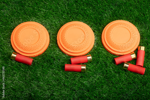 Clay disc flying targets and shotgun bullets on green grass background ,Clay Pigeon target