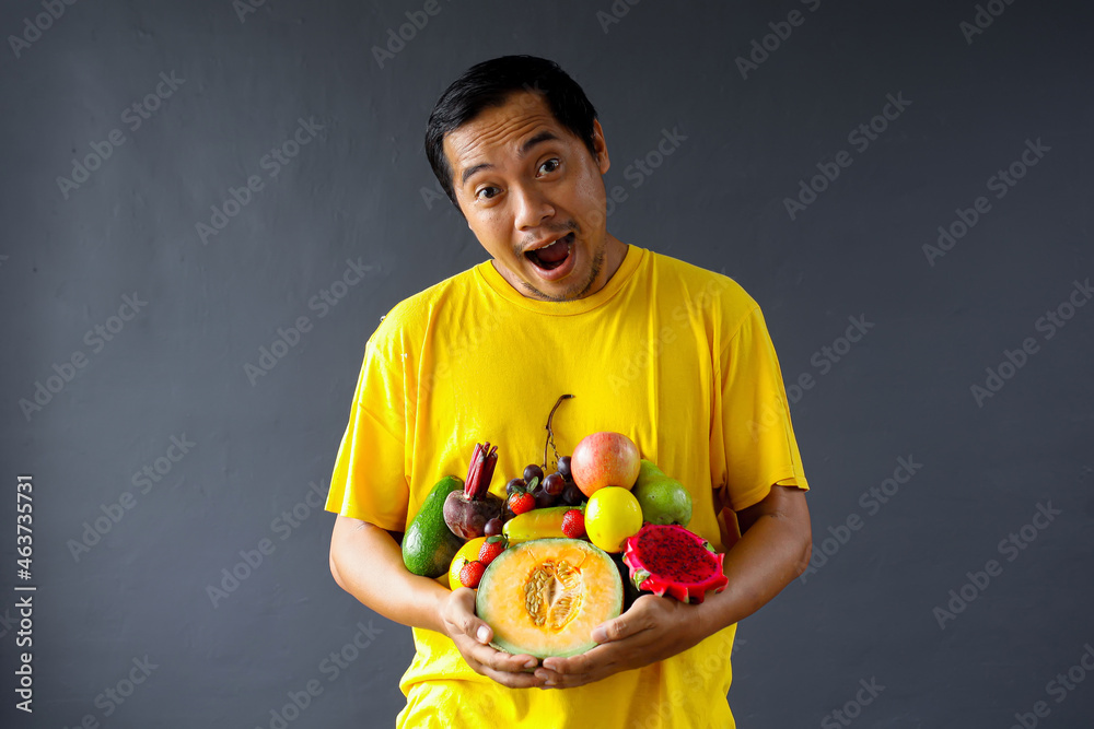 Happy Asian man holding assorted fresh fruits for healthy life style concept Happy Asian man holding assorted fresh fruits for healthy life style concept