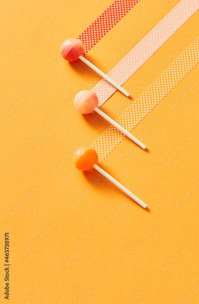 Three lollipops on a stick, at yellow background Three lollipops on a stick, at yellow background