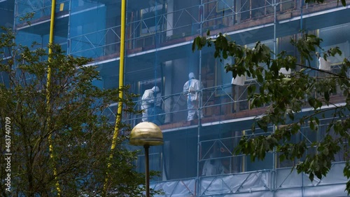 Asbestos abatement team Working on building, trees waving in foreground
 photo