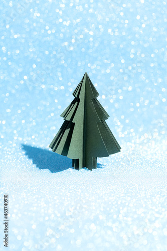 Christmas tree made of paper on a shiny blue background. Crafts by hand. Card