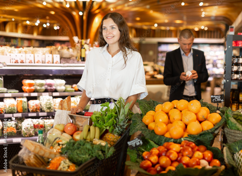 Woman with shopping cart choosing groceries in supermarket