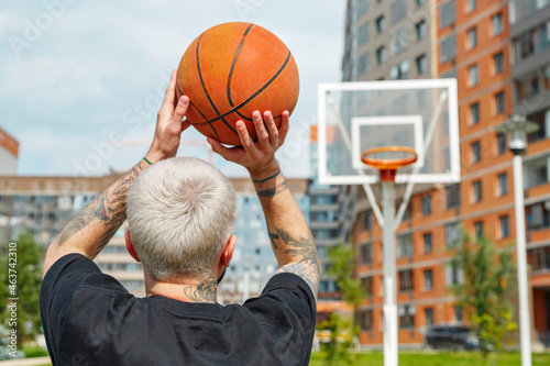 Unrecognizable man aiming at basketball hoop