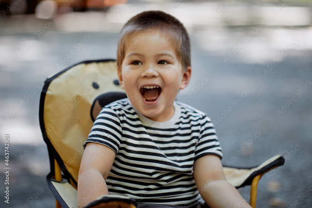 Foto de Cute Mixed Asian Boy Laughing Outside At A Barbecue do Stock