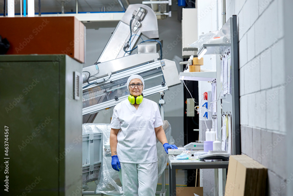 Female employee near conveyor at factory Female employee near conveyor at factory