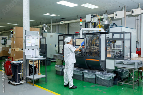 Woman operating machine at factory photo