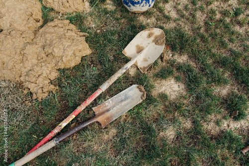 Two mud covered shovels laying on the ground.  photo