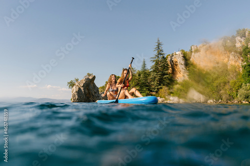 Two young women sitting on sup board photo