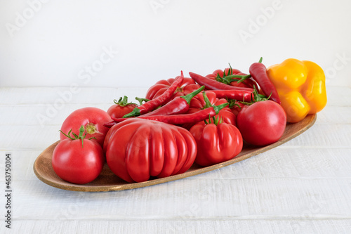 Ripe raw vegetables in dish on white rustic wooden table
