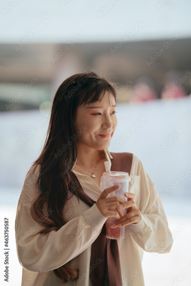 Asian woman with cup of juice on hand outdoors Asian woman with cup of juice on hand outdoors