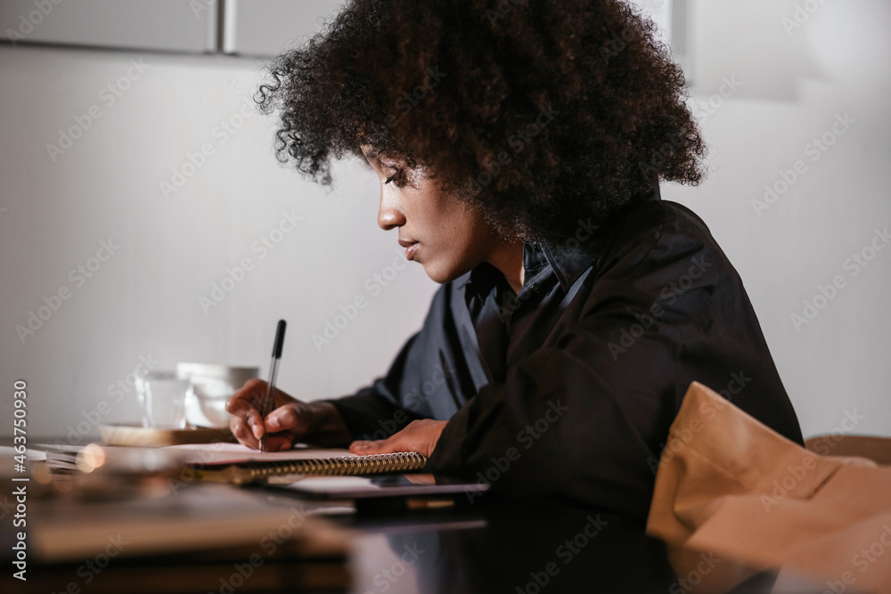 Black businesswoman writing in notebook Black businesswoman writing in notebook