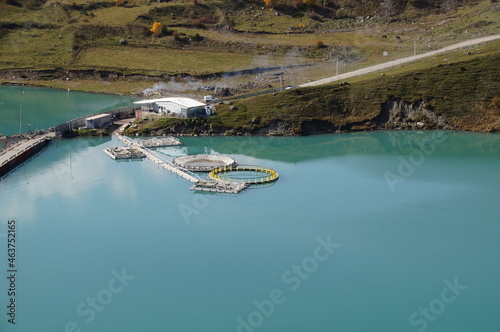 Trout breeding. Fish breeding in the reservoir. Blue water in the lake. Equipment on the water for growing fish. Fish farming in a lake high in the mountains.
