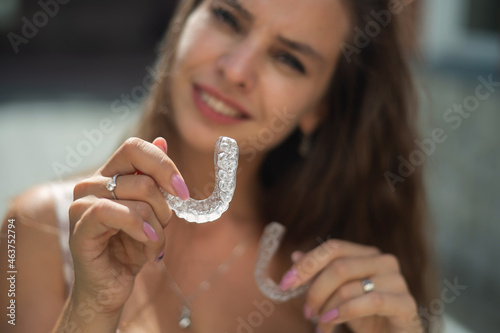 Beautiful caucasian woman holding transparent mouth guards for bite correction.