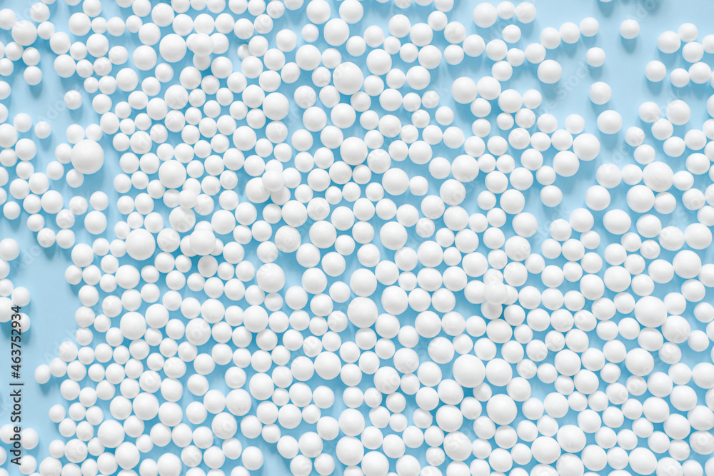 Abstract background consisting of spheres of white color on blue paper top view. Minimal arrangement of small circles.