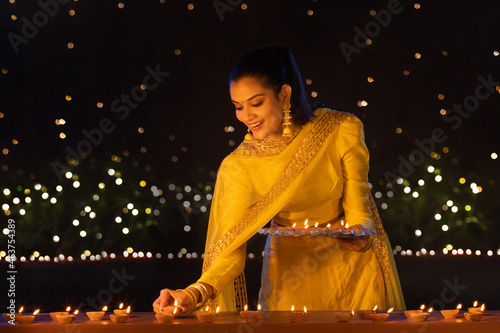 Young girl decorating house by diyas on the occasion of Diwali photo