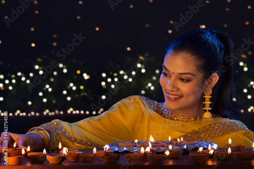 Beautiful Indian girl placing diyas with smile on the occasion of Diwali photo