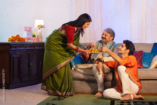 Woman giving ladoos to her husband and son on Diwali photo