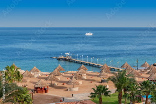 Fototapeta Naklejka Na Ścianę i Meble -  Aerial view of  Sunny beach in tropical resort with palm trees and umbrellas, Sharm Al Sheikh, Egypt, Africa.	