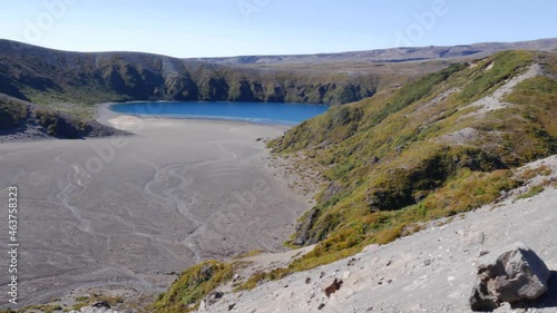 Pan across blue lake oasis on pumice ash volcanic mountain slope photo