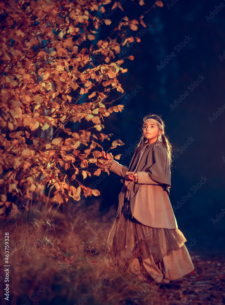 Young girl in national costume in the mystery fall night forest