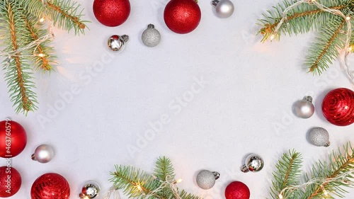 Blinking Christmas lights on natural fir twigs with red and silver ornaments on silver theme. Stop motion