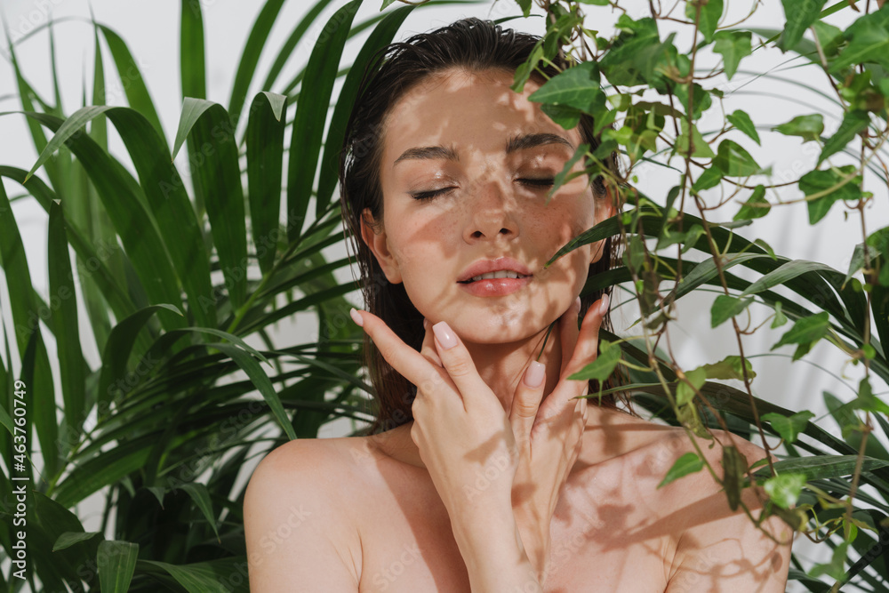 Young half-naked woman posing with plants on camera Young half-naked woman posing with plants on camera