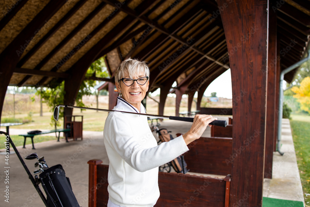 Portrait of female senior golfer standing on golf course and smiling. Portrait of female senior golfer standing on golf course and smiling.