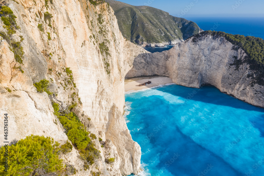 Aerial view of beautiful Navagio or Shipwreck beach on Zakynthos Island, Greece. Tourists on cliff edge enjoy view on summer travel trip