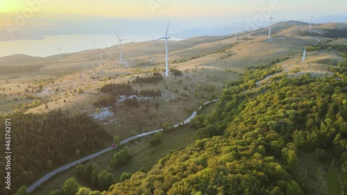 Electric car driving in countryside near wind turbines, sustainable concept photo