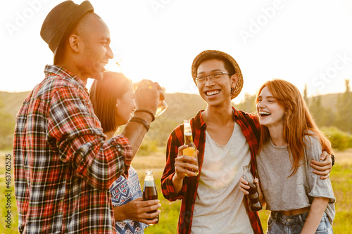Multiracial two couples drinking beverages and laughing while hiking