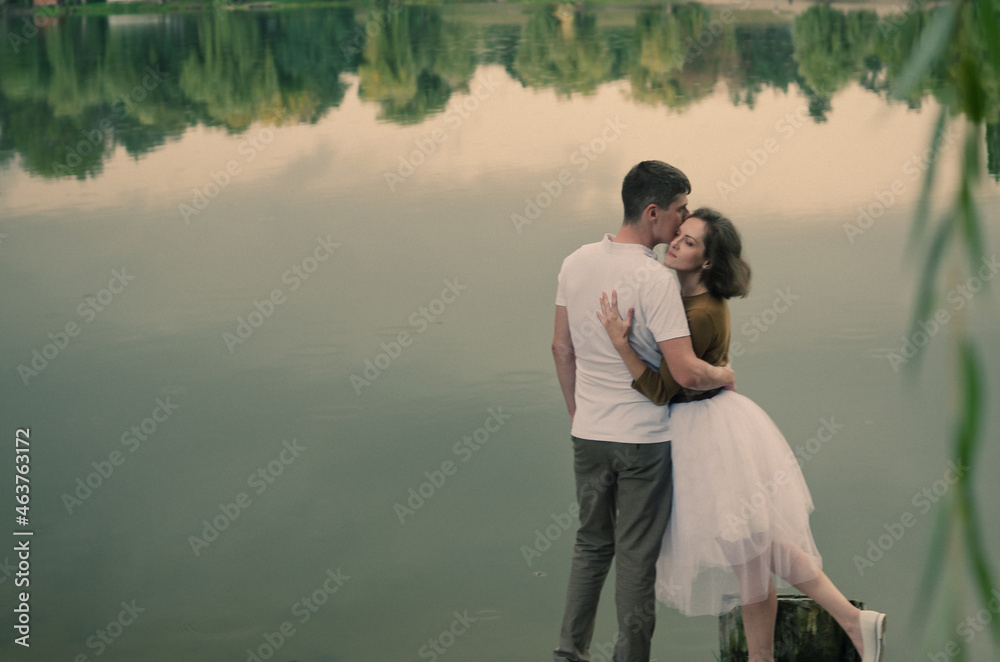 Love story of funny couple walking near river in hard rainfall with umbrella. cute man and woman in white skirt, yellow sweater. Family holiday and togetherness, date.