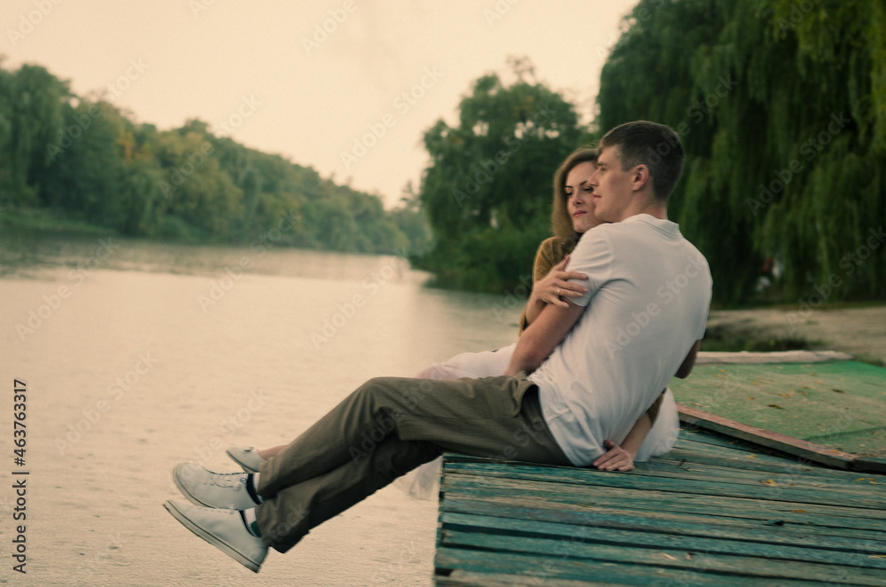 Love story of funny couple walking near river in hard rainfall with umbrella. cute man and woman in white skirt, yellow sweater. Family holiday and togetherness, date. Love story of funny couple walking near river in hard rainfall with umbrella. cute man and woman in white skirt, yellow sweater. Family holiday and togetherness, date.