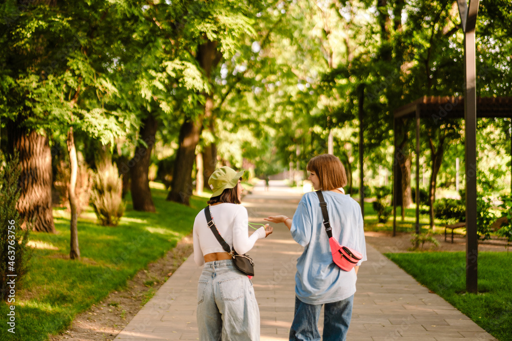 Multiracial two women talking and gesturing while walking together Multiracial two women talking and gesturing while walking together