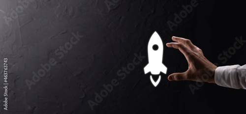 Male hand holding rocket icon that takes off, launch on blue background. rocket is launching and flying out, Business start up, Icon marketing on modern virtual interface.Start up concept.