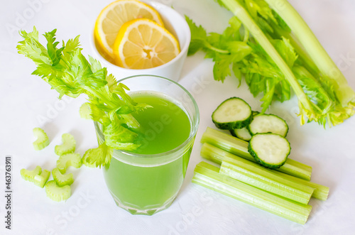 Green fresh celery and cucumber juice with lemon limtizers. Ingredients for a healthy drink, a glass of drink on a white background. Detox diet, pure organic food, with vegetables