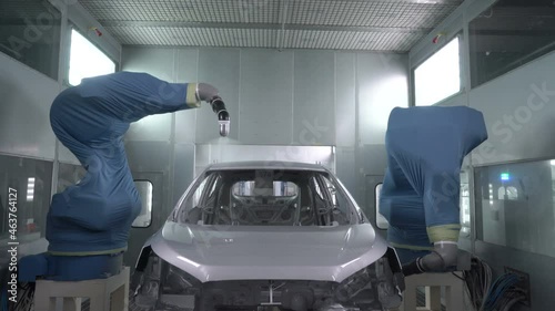 Robotic arms spray painting a vehicle body at a car manufacturing factory