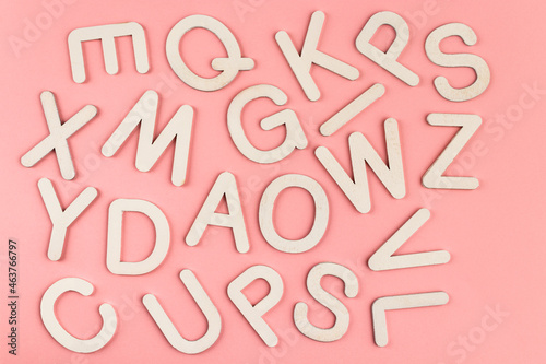 Wooden alphabet letters on pink paper background.