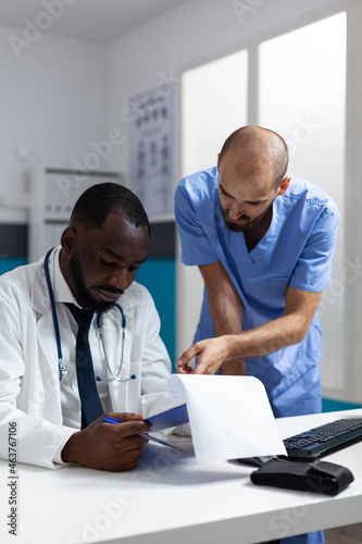 African american physician doctor analyzing clinical documents discussing medicine prescription working at healthcare treatment in hospital office. Therapist man nurse monitoring sickness expertise