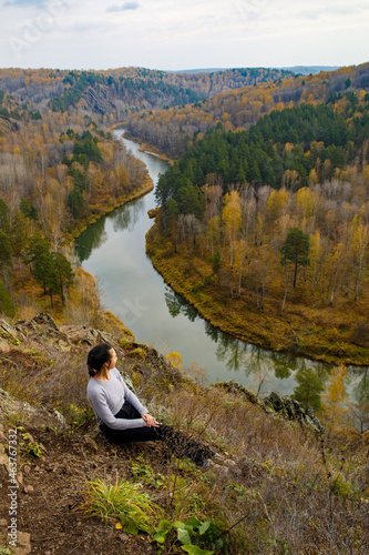 Woman hiker sitting on rock on top of mountain watching beautiful scenery of backcountry of Berd river, Novosibirsk region, Russia. Location: Zveroboy trail, Berdskie skaly, Novosibirsk, vertical photo