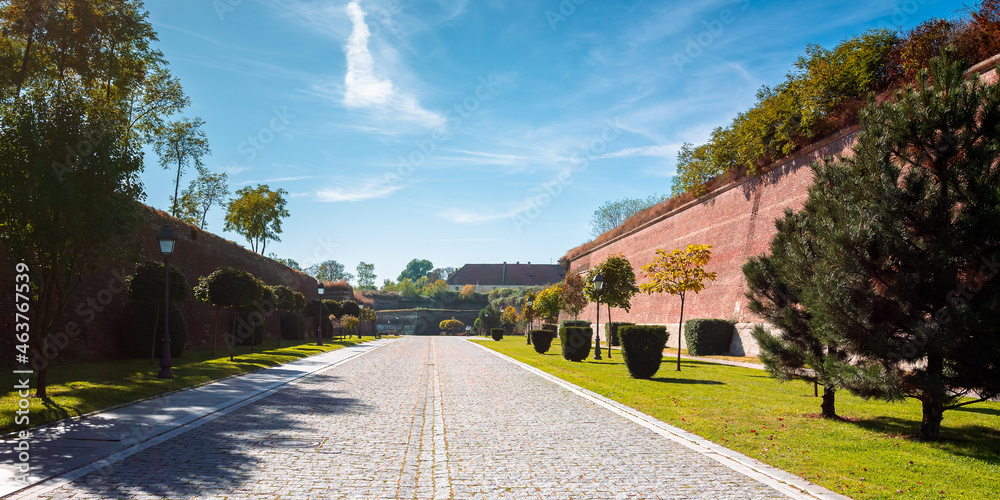 Fototapeta premium alba-iulia, romania - OCT 13, 2019: inner streets of alba carolina citadel in autumn. lanterns and benches by the walkway. huge walls around the path. popular travel destination