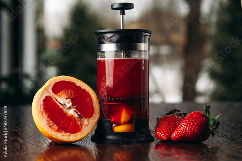 Red french press tea with grapefruit and strawberry on the table in restaurant photo