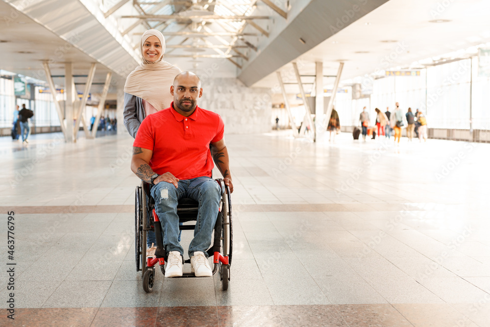 Obraz premium Muslim woman and disabled man looking at camera at train station