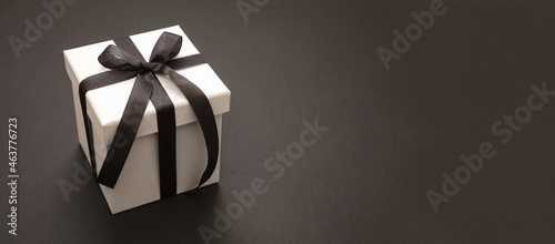 Gift box with black ribbon against dark background, banner. Black Friday sale concept,