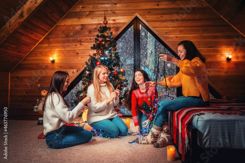 Christmas and new year. A group of young happy women socialize and untangle the lights. Scandinavian style interior