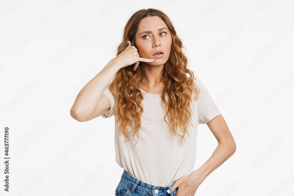 Young ginger woman in t-shirt frowning and making handset gesture Young ginger woman in t-shirt frowning and making handset gesture
